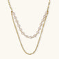 Layered gold chain necklace with organic baroque freshwater pearls and adjustable length on cream background